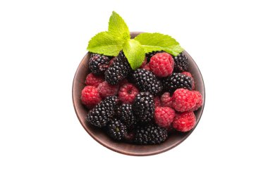 Ahududu, böğürtlen ve nane yaprağı seramik kahverengi kâsede beyaz arka planda izole edilmiş..  