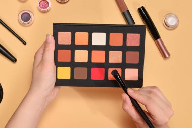 Kadın elinde göz farı paleti. Profesyonel makyaj ürünleri kozmetik güzellik ürünleri, vakıf, ruj, göz farı, fırça ve aletler.
