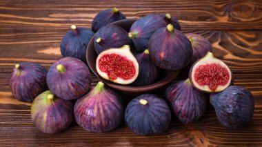 Ahşap arka planda bir kasede lezzetli incirler. Üst Manzara. Dilimler.  