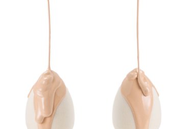 Beyaz arka planda izole edilmiş yeni beyaz süngerin üzerine dökülen sıvı bej makyaj vakfı