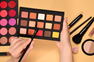 Kadın elinde göz farı paleti. Profesyonel makyaj ürünleri kozmetik güzellik ürünleri, vakıf, ruj, göz farı, fırça ve aletler.