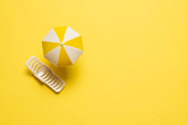 Sarı arka planda güneş ışığı ve sarı şemsiye..