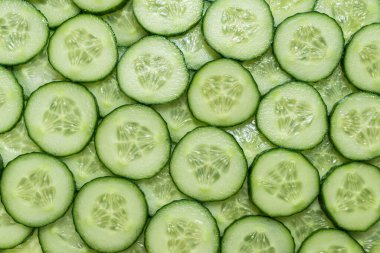 Arka plan olarak taze yeşil salatalık dilimleri. Üst görünüm. 