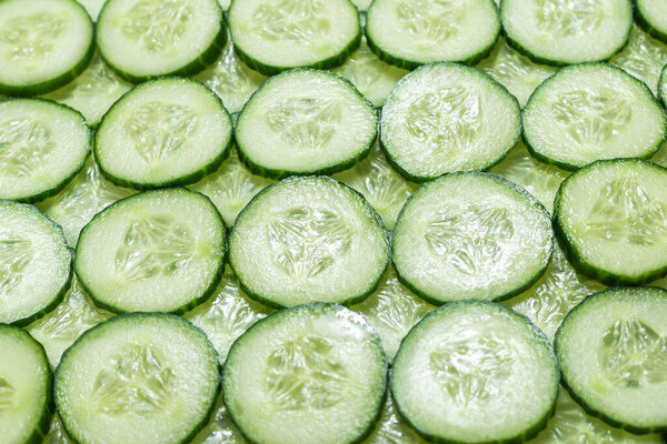 Fresh green slices of cucumber as background. Top view. 