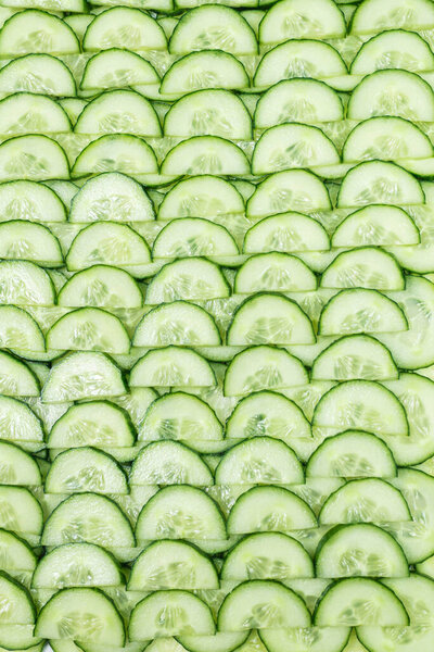 На заднем плане зеленые дольки огурца. Вид сверху. 