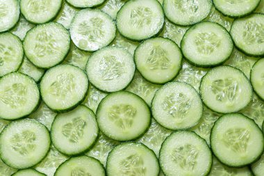 Arka plan olarak taze yeşil salatalık dilimleri. Üst görünüm. 