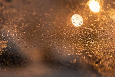 Yağmur damlaları ve ışıklarla bulanık arkaplan.