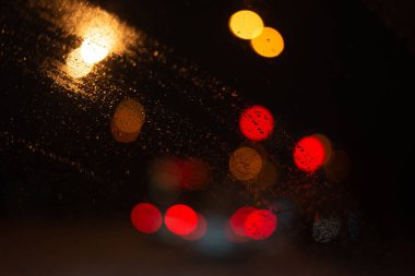 Yağmur damlaları ve ışıklarla bulanık arkaplan.