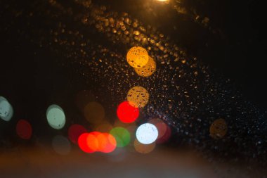 Yağmur damlaları ve ışıklarla bulanık arkaplan.