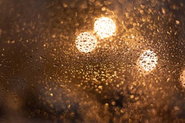 Yağmur damlaları ve ışıklarla bulanık arkaplan.
