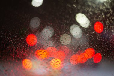 Yağmur damlaları ve ışıklarla bulanık arkaplan.