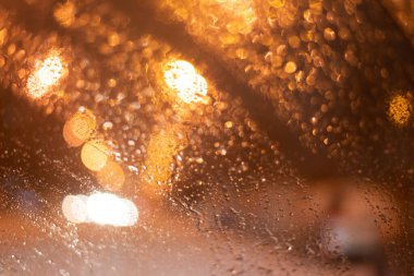 Yağmur damlaları ve ışıklarla bulanık arkaplan.