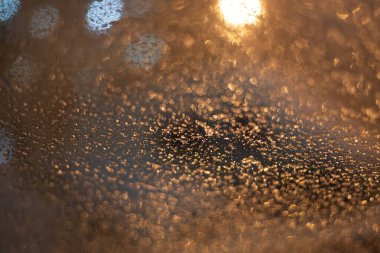 Yağmur damlaları ve ışıklarla bulanık arkaplan.