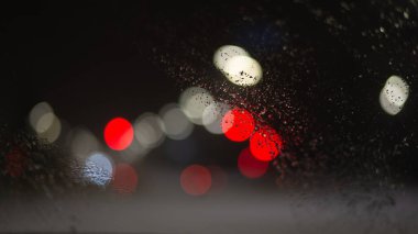 Yağmur damlaları ve ışıklarla bulanık arkaplan.