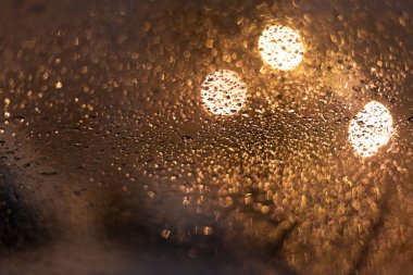 Yağmur damlaları ve ışıklarla bulanık arkaplan.