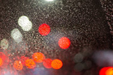 Yağmur damlaları ve ışıklarla bulanık arkaplan.