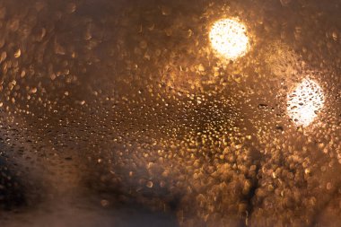 Yağmur damlaları ve ışıklarla bulanık arkaplan.