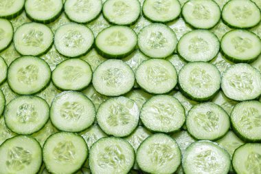 Arka plan olarak taze yeşil salatalık dilimleri. Üst görünüm. 