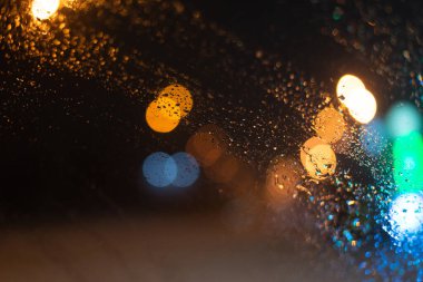 Yağmur damlaları ve ışıklarla bulanık arkaplan.