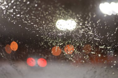 Yağmur damlaları ve ışıklarla bulanık arkaplan.