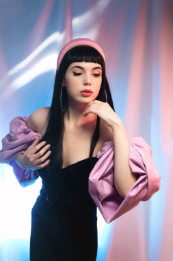 Neon ışınlarının arka planında modaya uygun pembe renkli kolları olan, bluzlu şık, flörtöz bir esmer. Büyüleyici bir stil.