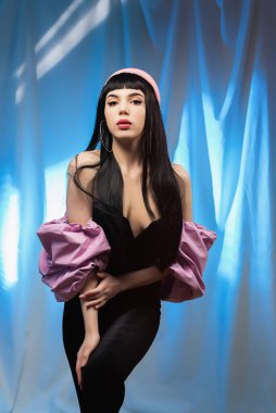 Neon ışınlarının arka planında modaya uygun pembe renkli kolları olan, bluzlu şık, flörtöz bir esmer. Büyüleyici bir stil.