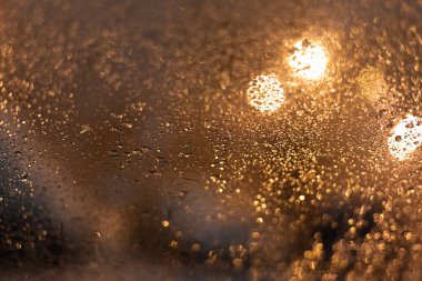 Yağmur damlaları ve ışıklarla bulanık arkaplan.