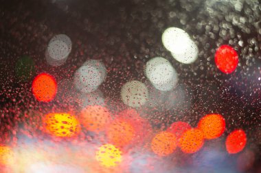 Yağmur damlaları ve ışıklarla bulanık arkaplan.