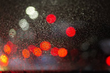 Yağmur damlaları ve ışıklarla bulanık arkaplan.