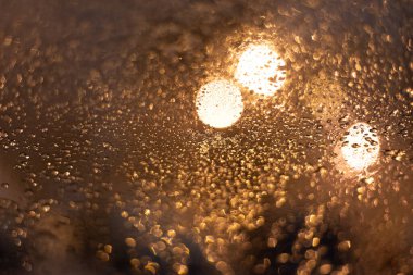 Yağmur damlaları ve ışıklarla bulanık arkaplan.