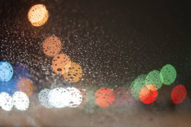 Yağmur damlaları ve ışıklarla bulanık arkaplan.