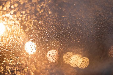 Yağmur damlaları ve ışıklarla bulanık arkaplan.