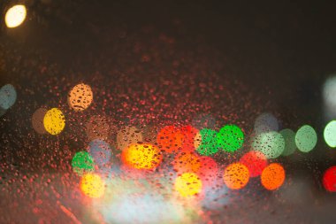 Yağmur damlaları ve ışıklarla bulanık arkaplan.