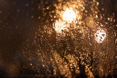 Yağmur damlaları ve ışıklarla bulanık arkaplan.