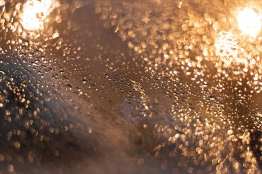 Yağmur damlaları ve ışıklarla bulanık arkaplan.