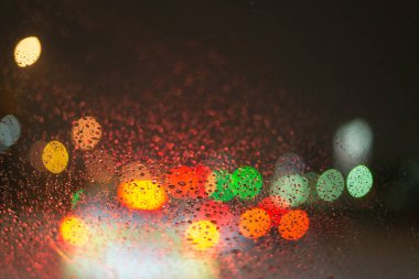 Yağmur damlaları ve ışıklarla bulanık arkaplan.