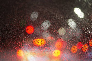 Yağmur damlaları ve ışıklarla bulanık arkaplan.