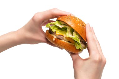 Hamburger, beyaz bir arka planda izole edilmiş bir şekilde kadınların elinde. Üst görünüm. 