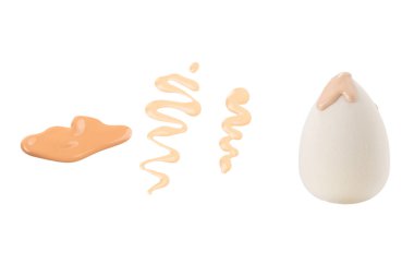 Beyaz arka planda izole edilmiş yeni beyaz süngerin üzerine dökülen sıvı bej makyaj vakfı