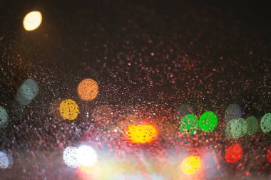 Yağmur damlaları ve ışıklarla bulanık arkaplan.