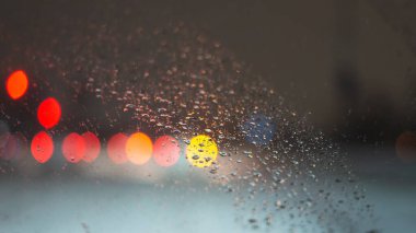 Yağmur damlaları ve ışıklarla bulanık arkaplan.