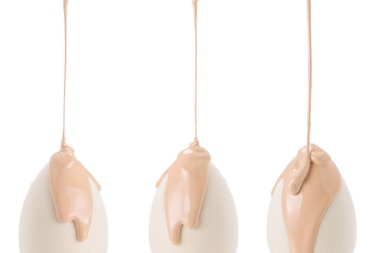 Beyaz arka planda izole edilmiş yeni beyaz süngerin üzerine dökülen sıvı bej makyaj vakfı