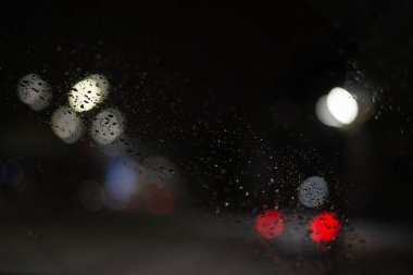 Yağmur damlaları ve ışıklarla bulanık arkaplan.