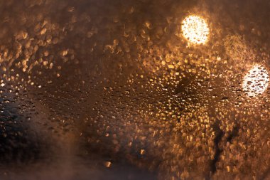 Yağmur damlaları ve ışıklarla bulanık arkaplan.