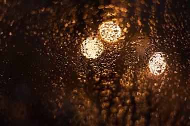 Yağmur damlaları ve ışıklarla bulanık arkaplan.