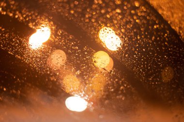 Yağmur damlaları ve ışıklarla bulanık arkaplan.