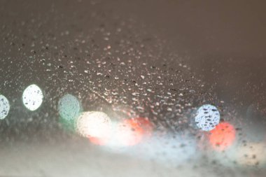 Yağmur damlaları ve ışıklarla bulanık arkaplan.