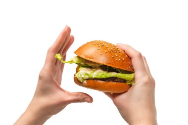 Hamburger, beyaz bir arka planda izole edilmiş bir şekilde kadınların elinde. Üst görünüm. 