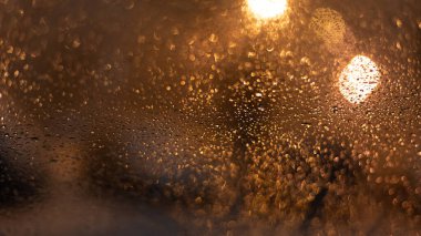 Yağmur damlaları ve ışıklarla bulanık arkaplan.