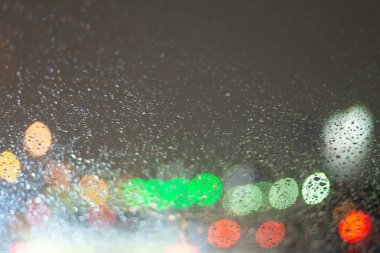 Yağmur damlaları ve ışıklarla bulanık arkaplan.